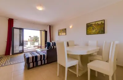 a living room with a table and chairs and a couch at Paraísos do Pinhal - 2 Bedrooms - Vilamoura in Vilamoura