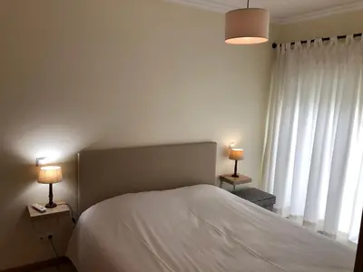 a bedroom with a bed and two lamps on tables at Apartamentos Pomba Branca in Olhos de Água