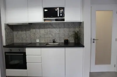 a kitchen with white cabinets and a sink and a microwave at Paz na Areia in Quarteira