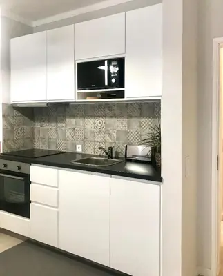a kitchen with white cabinets and a sink at Paz na Areia in Quarteira