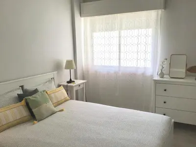 a bedroom with a white bed and a window at Paz na Areia in Quarteira