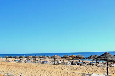 a beach with chairs and umbrellas and the ocean at Quarteira Beach Holidays in Quarteira