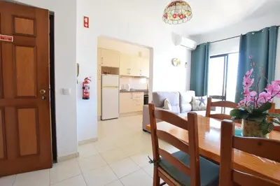 a living room with a dining room table and a kitchen at Apartamentos Carruna in Albufeira