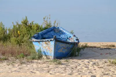 a blue boat sitting on the sand on the beach at Apartamentos Carruna in Albufeira