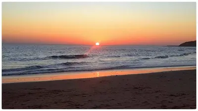 a sunset on the beach with the sun setting at Casa do Mar by Laranjal Rentals in Albufeira