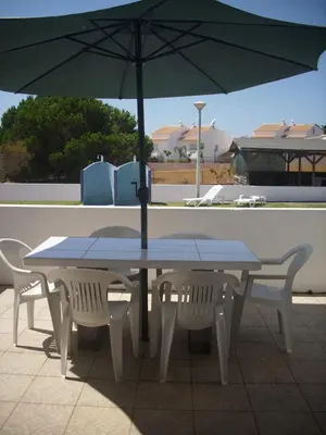 a table and chairs with an umbrella on a patio at Vila Olímpica in Albufeira