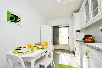a white kitchen with a white table and chairs at Apartment Ipanema 3 by Algarve Vacation in Albufeira