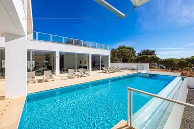 a swimming pool with chairs and a house at Villa Ocean Pine in Albufeira