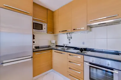 a kitchen with wooden cabinets and stainless steel appliances at Mar apartment wonderful view - Quarteira in Quarteira