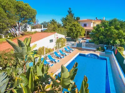a swimming pool with blue chairs and a house at Villa Honolulu by Algarve Vacation in Albufeira