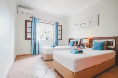 two beds in a room with blue curtains at Villa Honolulu by Algarve Vacation in Albufeira