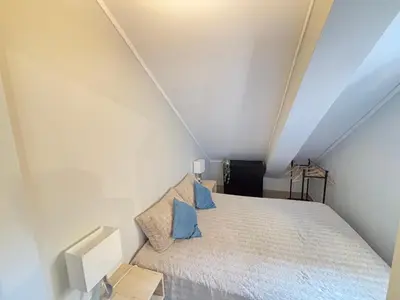 a small attic bedroom with a bed with blue pillows at The Marina Plaza Vilamoura in Vilamoura