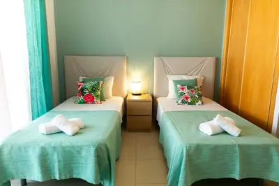 two beds in a room with green sheets and pillows at Sunny Condo-Pool by Algarve Dream Holidays in Albufeira