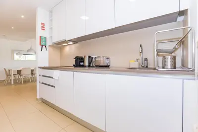 a kitchen with white cabinets and a sink at Cavalo Preto Luxury Beach Apartment by Golden Zenith in Quarteira
