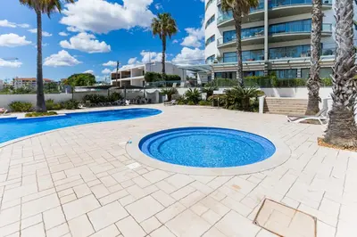 a pool with palm trees and a building at Cavalo Preto Luxury Beach Apartment by Golden Zenith in Quarteira
