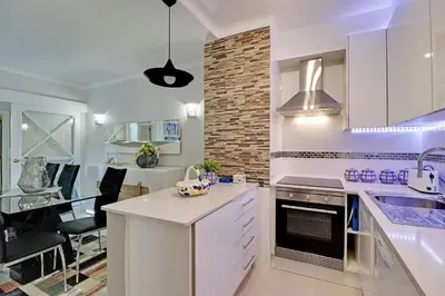 a kitchen with white cabinets and a dining room at Vilamoura Design 1 with Pool by Homing in Vilamoura