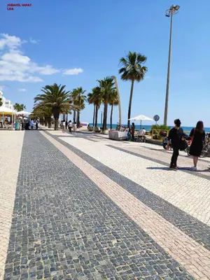 a cobblestone street with palm trees on the beach at Alsol C 5365-1 in Quarteira