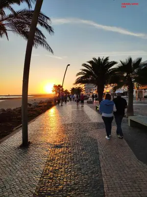 a group of people walking down a sidewalk near the beach at Alsol C 5360 in Quarteira
