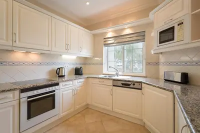 a kitchen with white cabinets and a sink and a window at Aleisha in Vale do Lobo
