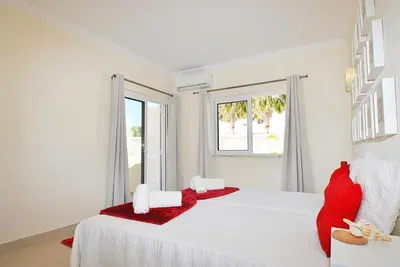 a white bedroom with a large white bed with red pillows at Villa Moorea by Algarve Vacation in Guia