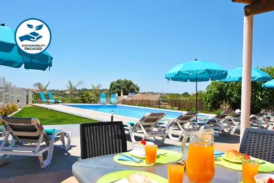 a table with food and orange juice next to a swimming pool at Villa Zanzibar by Algarve Vacation in Olhos de Água