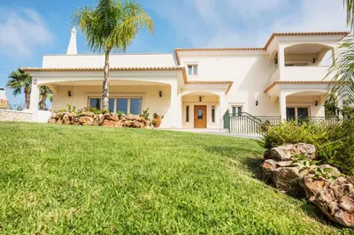 a large white house with a palm tree at Villa Pauline by Algarve Vacation in Albufeira