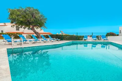 a swimming pool with blue lounge chairs and a tree at Villa Kailua by Algarve Vacation in Albufeira