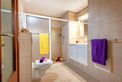 a bathroom with a toilet and a shower with purple towels at Villa Morais by Algarve Vacation in Guia
