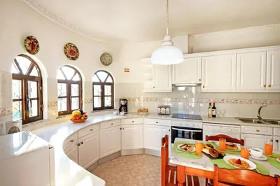 a kitchen with white cabinets and a table with chairs at Villa Morais by Algarve Vacation in Guia