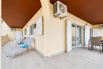 a white bed with an orange blanket and two lamps at Palmeira Galé Apartment in Albufeira