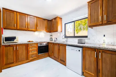 a kitchen with wooden cabinets and white appliances at Villa Crisandra by Algarve Vacation in Albufeira