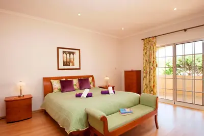 a bedroom with a bed and a couch and a window at Villa Savannah by Algarve Vacation in Almancil