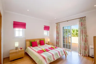 a bedroom with a large bed with two pink pillows at Villa Savannah by Algarve Vacation in Almancil