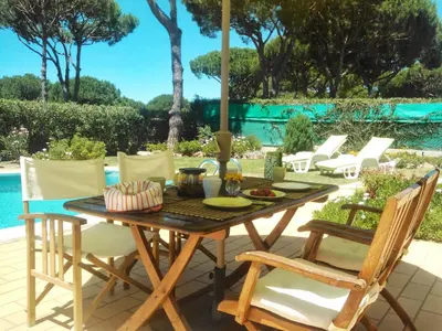 a wooden table and chairs on a patio with a pool at Alsouk in Vilamoura