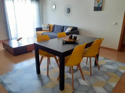 a living room with a black table and yellow chairs at Apartamento Alfarrobeira Mar in Quarteira