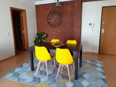 a dining room with a black table and yellow chairs at Apartamento Alfarrobeira Mar in Quarteira