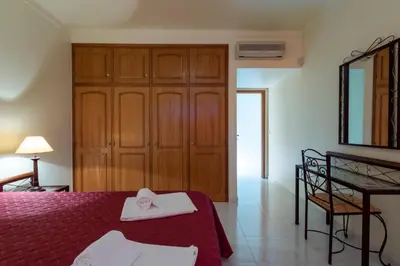 a bedroom with a bed and a wooden cabinet at Villa with Garden and Pool in Vilamoura