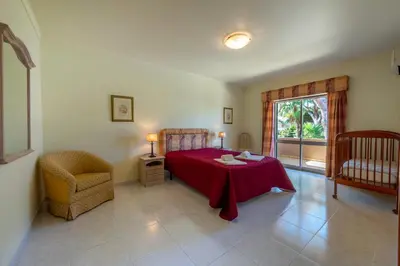a bedroom with a bed and a table and a chair at Villa with Garden and Pool in Vilamoura