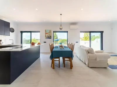 a kitchen and living room with a table and a couch at Casa O Sonho near Faro with private pool in Santa Bárbara de Nexe