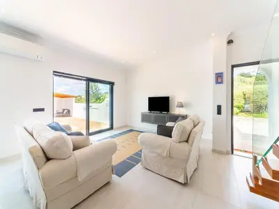 a living room with two chairs and a tv at Casa O Sonho near Faro with private pool in Santa Bárbara de Nexe