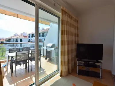 a living room with a television and a balcony at Sunny Balcony Apartment and Pool in Vilamoura