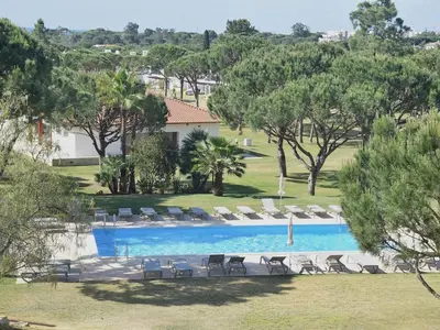 a swimming pool with lounge chairs and trees at Sunny Balcony Apartment and Pool in Vilamoura