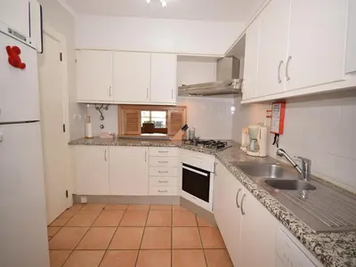 a kitchen with white cabinets and a sink at Sunny Balcony Apartment and Pool in Vilamoura