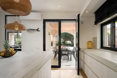 a kitchen with a counter and a dining room at Villa Coral - Varandas do Lago in Almancil