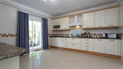 a kitchen with white cabinets and a large window at Villa Natura - Varandas do Lago in Almancil