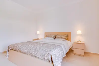 a white bedroom with a bed and a dresser at Tália - City Center - Vilamoura in Vilamoura