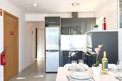 a kitchen with a refrigerator and a table with wine glasses at Edifico Ouramar T2 in Albufeira