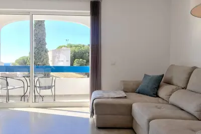 a living room with a couch and a balcony at Edifico Ouramar T2 in Albufeira