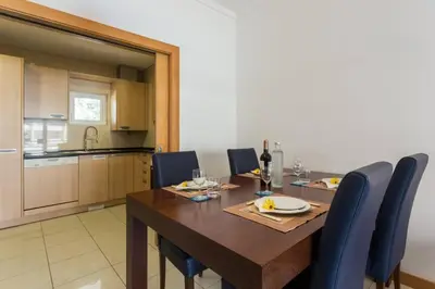 a dining room with a wooden table and blue chairs at Quinta Barracuda in Albufeira