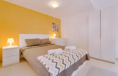 a bedroom with a large bed and a yellow wall at Cruzeiro do Sul Apartments - Vilamoura center in Vilamoura
